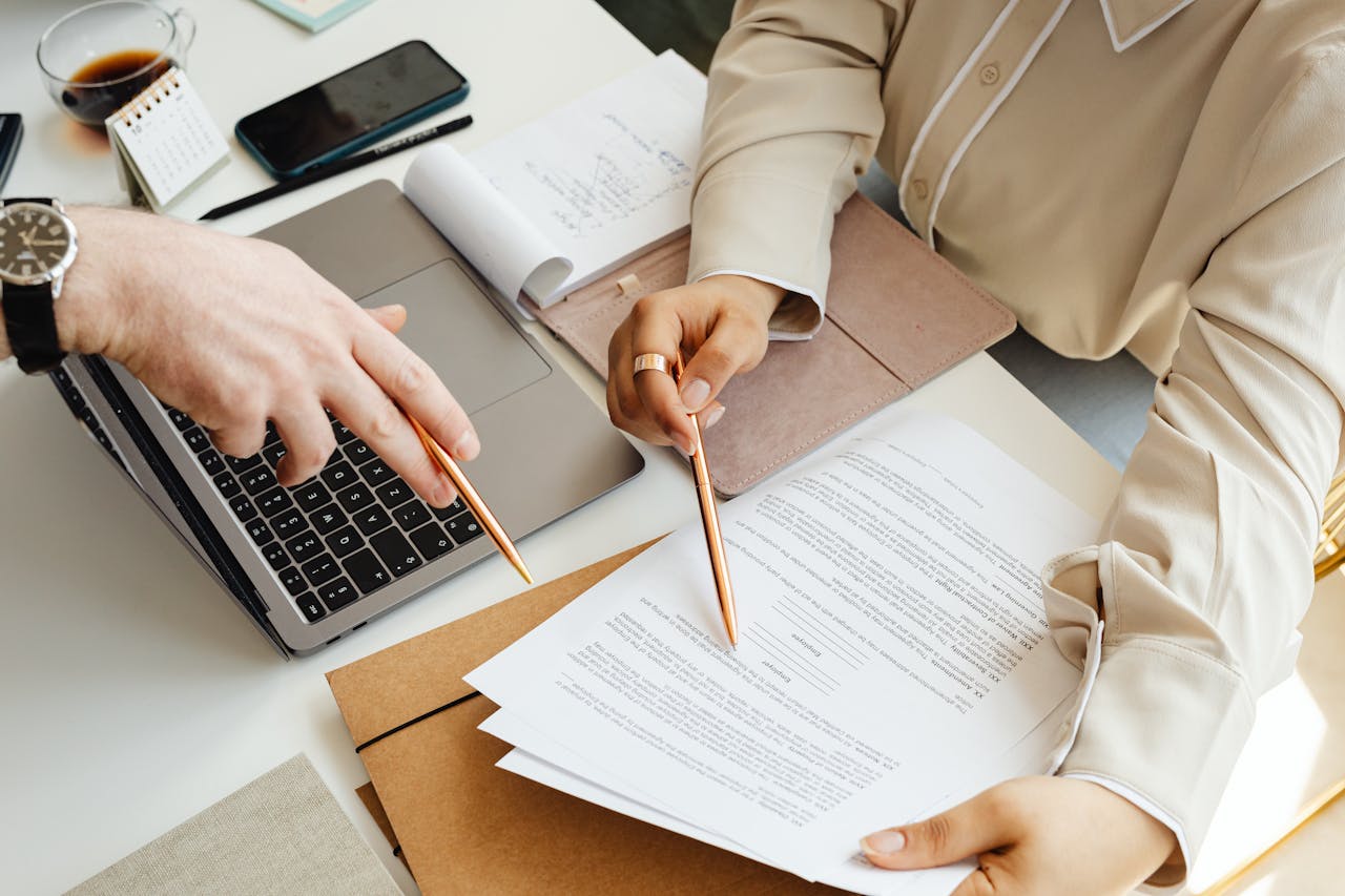 Office teamwork with two people reviewing documents and using a laptop